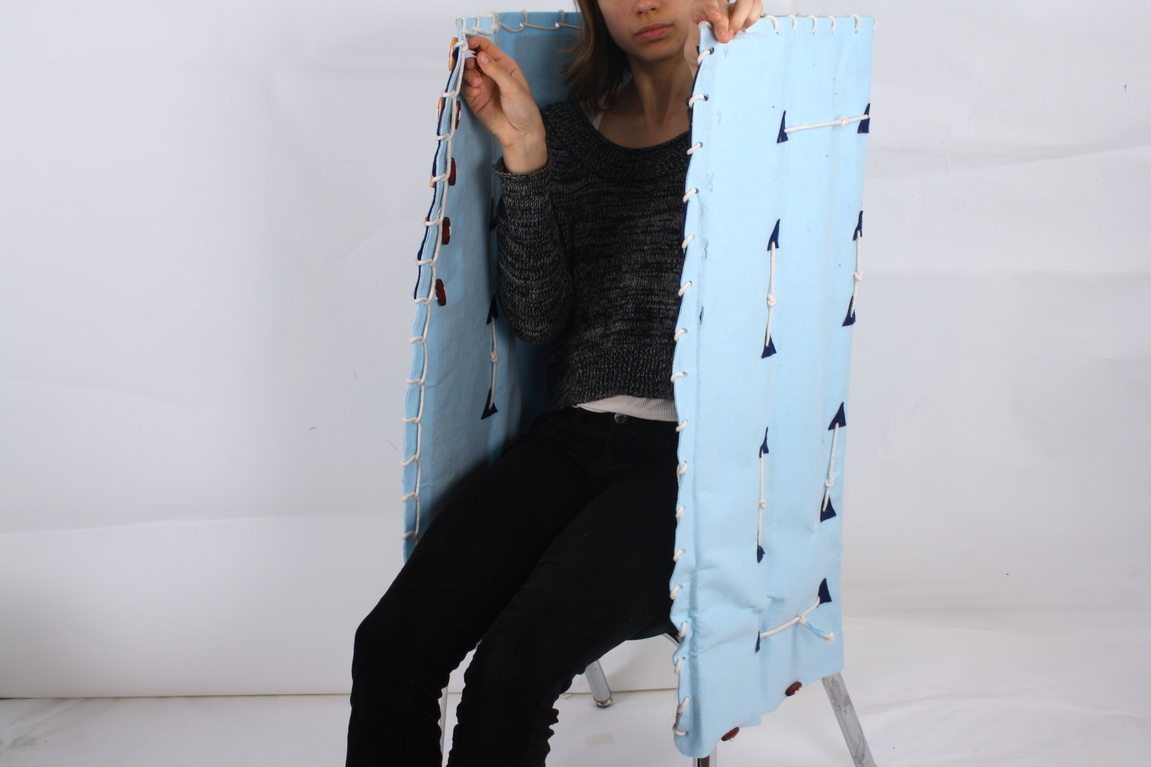 An Olin student models sitting in the chair with felted canopy drawn close, the height of which would provide total coverage for a school-age child.